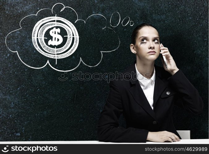 Troubled businesswoman. Young upset businesswoman sitting at table and talking on mobile phone