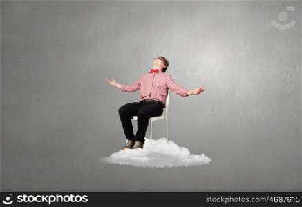 Troubled young man sitting in chair on cloud. Being in despair