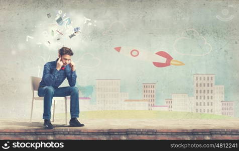 Troubled young man sitting in chair outdoors