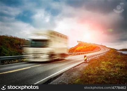 "Truck and highway at sunset. Truck Car in motion blur. Atlantic Ocean Road or the Atlantic Road (Atlanterhavsveien) been awarded the title as "Norwegian Construction of the Century"."