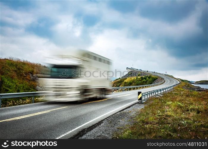 "Truck and highway at sunset. Truck Car in motion blur. Atlantic Ocean Road or the Atlantic Road (Atlanterhavsveien) been awarded the title as "Norwegian Construction of the Century"."