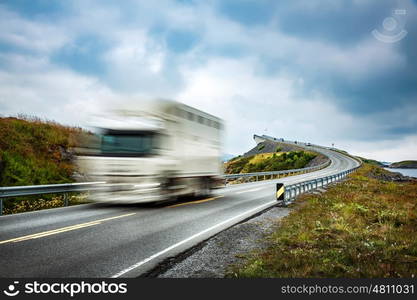 "Truck and highway at sunset. Truck Car in motion blur. Atlantic Ocean Road or the Atlantic Road (Atlanterhavsveien) been awarded the title as "Norwegian Construction of the Century"."