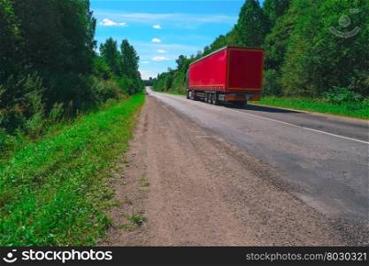 Truck on empty highway with green forest on both sides. Truck on empty highway