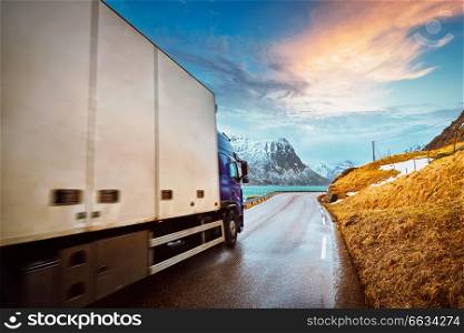 Truck on road in Norwegian fjord on sunset. Lofoten islands, Norway. Motion blur. Truck on road in Norway