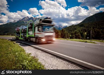 Truck trailer transports new cars rides on highway. Truck trailer transports new cars rides on highway, Italy natural landscape Alps. Warning - authentic shooting there is a motion blur.