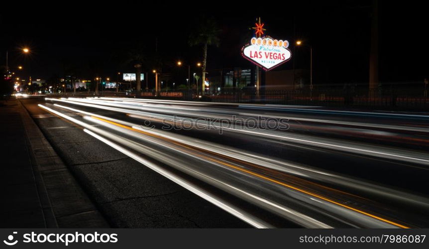 Trucks and Cars whiz by the sign welcoming all to Las Vegas