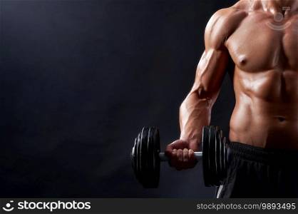 True hard worker. Cropped closeup of a strong muscular male holding a dumbbell posing against black background. Young fitness man in studio