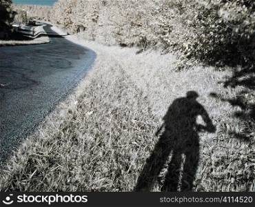 True infrared picture of curvy road in the countryside with cyclist shadow