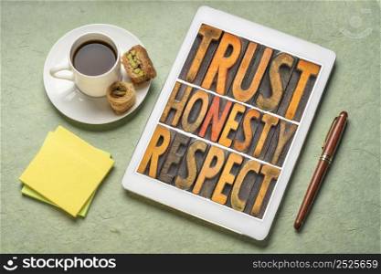 trust honesty and respect word abstract in vintage letterpress wood type on a digital tablet with cup of coffee, core values concept