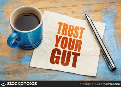 Trust your gut word abstract - advice or motivational reminder on a napkin with cup of espresso coffee