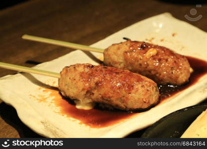 Tsukune filled with cheese serve with special sauce on white plate