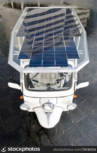 Tuc tuc with solar panels on its roof in a business district