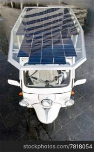 Tuc tuc with solar panels on its roof in a business district