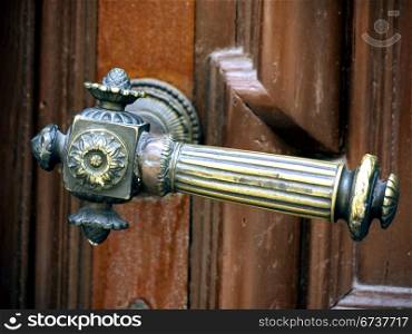 Tuerklinke-verziert. ornate door handle on a brown door