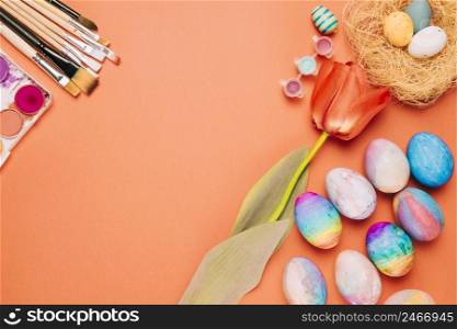 tulip flower paintbrushes colorful easter eggs nest orange background
