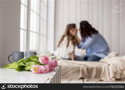 tulip flowers table near bed with hugging mother daughter