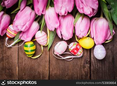 Tulips and eggs border over wooden backdrop. Easter decorations.
