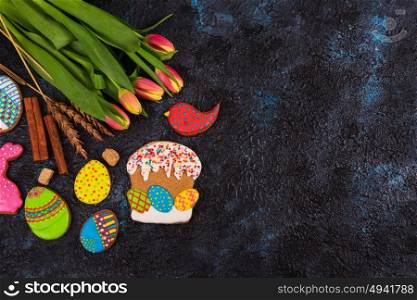 Tulips and gingerbread cookies on darken concrete background for Easter.. Tulips and gingerbread cookies