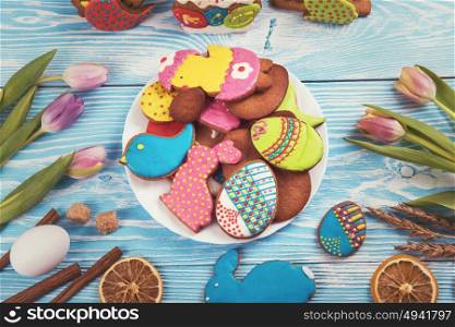 Tulips and gingerbread cookies on white and blue wooden background for Easter.. Happy Easter coming