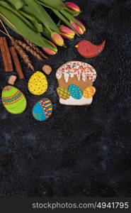 Tulips and gingerbread cookies. Tulips and gingerbread cookies on darken concrete background for Easter.