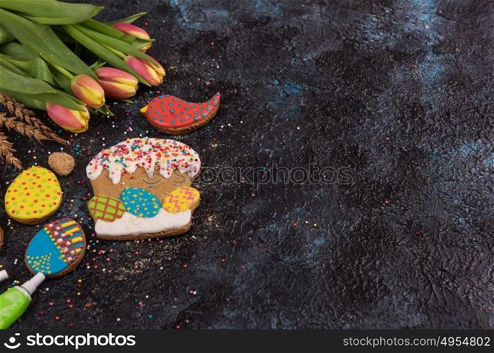 Tulips and gingerbread cookies. Tulips and gingerbread cookies on darken concrete background for Easter.