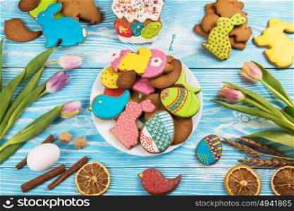 Tulips and gingerbread cookies. Tulips and gingerbread cookies on white and blue wooden background for Easter.