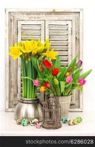 tulips and narcissus bouquet. home interior decoration with fresh spring flowers and colored easter eggs
