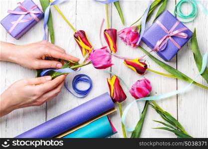 tulips and preparation of gifts. Hand packing gift and flowers for the holiday