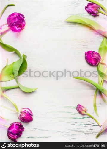 Tulips frame on light shabby chic background, top view, vertical. Spring flowers concept.