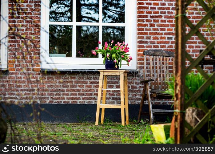 Tulips in a vase in the garden against the backdrop of a beautiful house