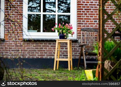 Tulips in a vase in the garden against the backdrop of a beautiful house