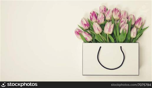 Tulips in shopping bag with space for text. Flat lay, top view