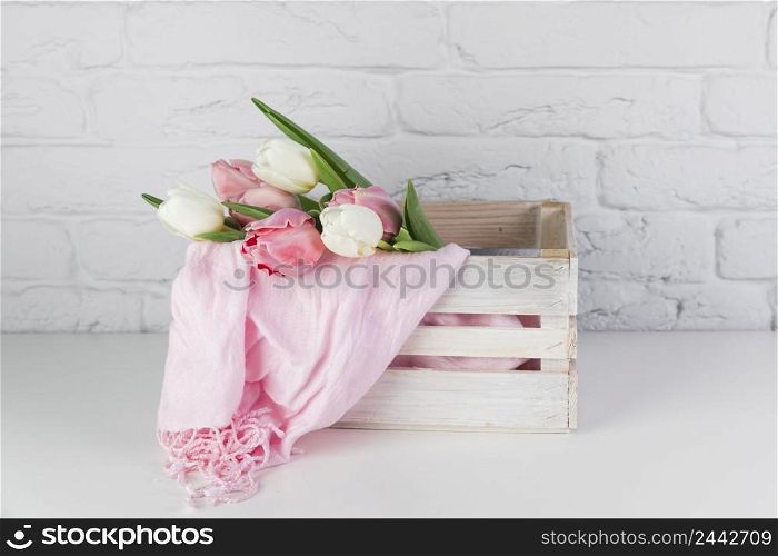tulips pink scarf inside wooden crate desk against white brick wall