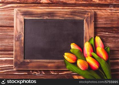 Tulips with chalkboard on a wooden background - spring greetings. Tulips with chalkboard