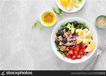Tuna and fresh vegetable salad of tomato, cucumber, olives, onion, lettuce and boiled egg, top view