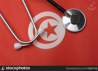 Tunisian flag and stethoscope. The concept of medicine. Stethoscope on the flag as a background.. Tunisian flag and stethoscope. The concept of medicine.