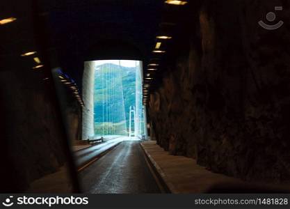 Tunnel at norwegian mountains and suspension bridge in the background. View from car. Infrastructure in Norway Scandinavia. tunnel exit and bridge in Norway