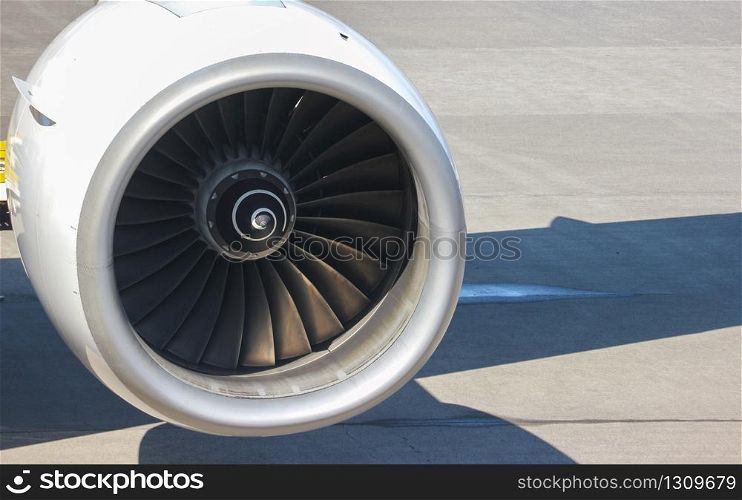 Turbine engine part of airplane with airport runway as background.