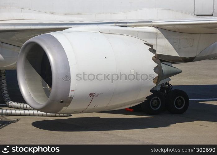Turbine engine part of airplane with airport runway as background.