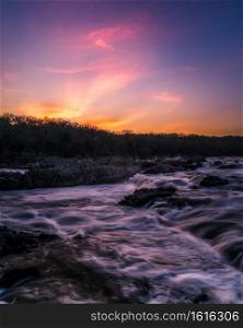 Turbulent waters of the Potomac River at Great Falls Park reflecting the glow of the colorful sunset.
