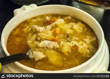 Tureen of spicy soup of pickled cabbage, pieces of pork and vegetables