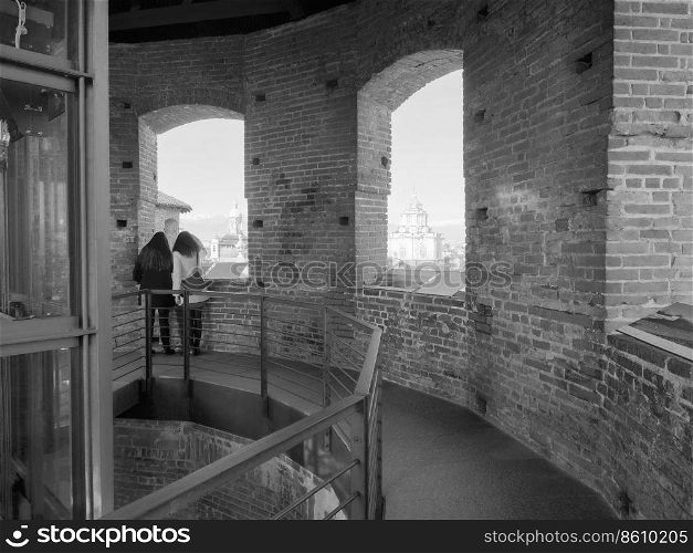 TURIN, ITALY - CIRCA FEBRUARY 2019  Women looking at the city from viewing platform on top of medieval tower in Piazza Castello in black and white. Women looking at the city from viewpoint in Turin in black and white