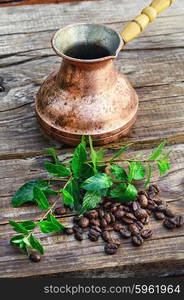 Turk and coffee beans. empty cezve on wooden background with scattered coffee beans and mint.