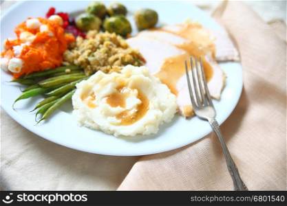 Turkey dinner with stuffing, gravy, mashed potatoes, green beans, sweet potatoes and brussels sprouts with napkin