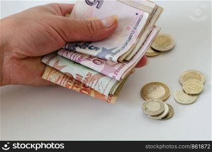 Turkish banknotes and coins are woman's hand on white background.