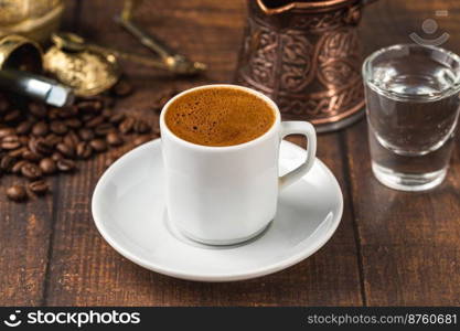 Turkish coffee in classic coffee cup with water and Turkish delight on wooden table