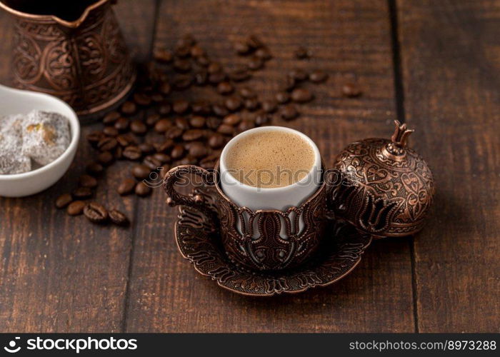 Turkish coffee in classic coffee cup with water and Turkish delight on wooden table