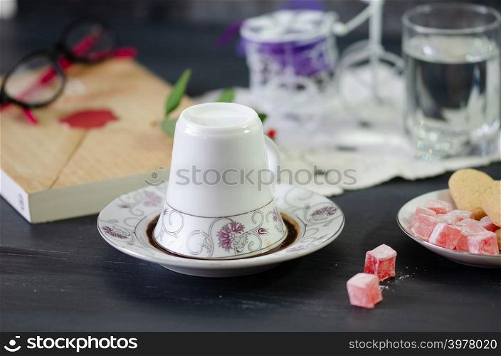 Turkish Coffee in White Porcelain Cup and Turkish Delight.Single overturned coffee cup on the plate for coffee divination