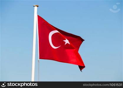 Turkish flag fluttering in the breeze against a bright blue sky, Bodrum, Turkey