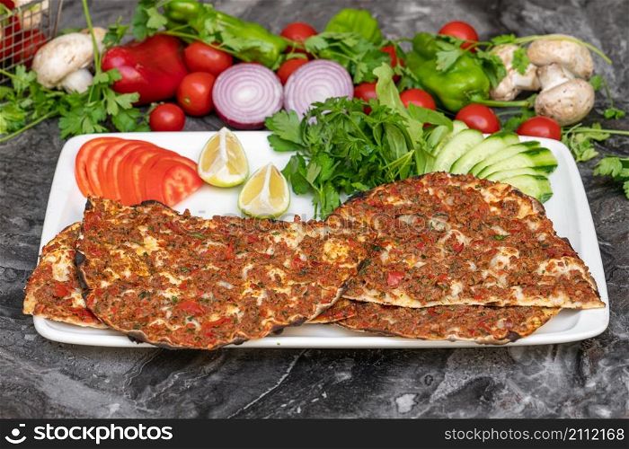 Turkish Lahmacun or Turkish pizza with tomato, parsley and lemon on marble table